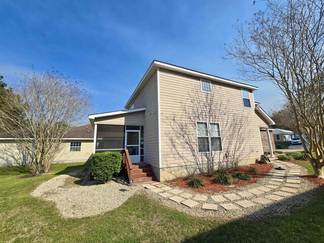 view of side of property featuring a sunroom and a lawn