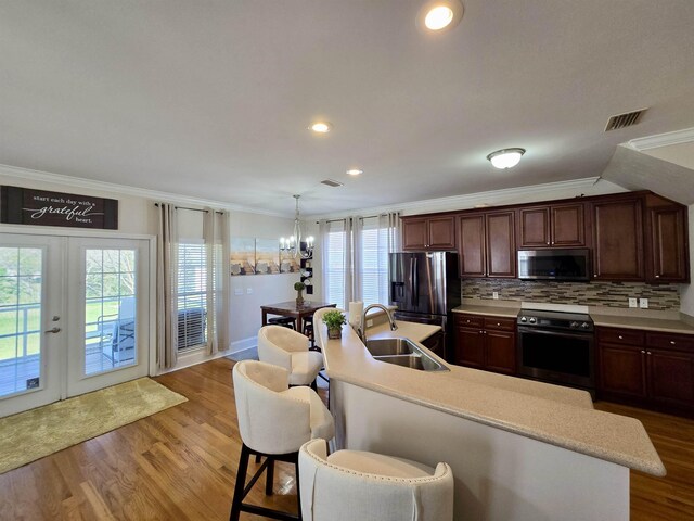 kitchen with light countertops, visible vents, crown molding, stainless steel appliances, and a kitchen breakfast bar