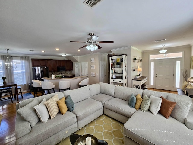 living room with visible vents, wood finished floors, and ornamental molding