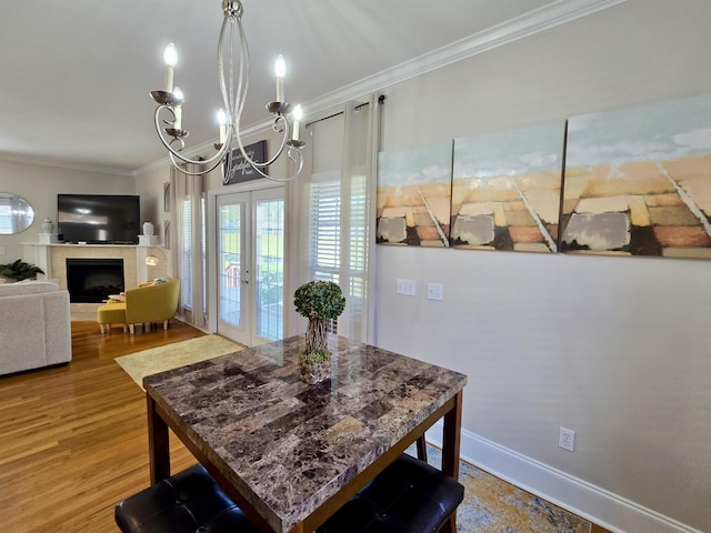 dining room with crown molding, baseboards, wood finished floors, an inviting chandelier, and french doors