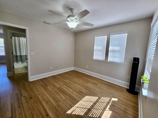 interior space featuring a ceiling fan, wood finished floors, baseboards, and visible vents