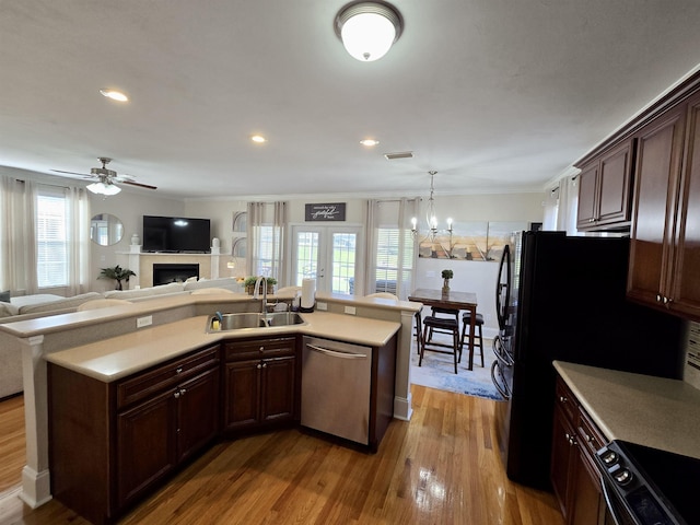 kitchen with light countertops, a sink, black range with electric cooktop, dishwasher, and wood finished floors