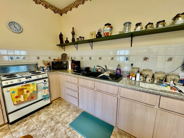 kitchen with sink, white gas range oven, light stone countertops, light tile patterned floors, and light brown cabinetry