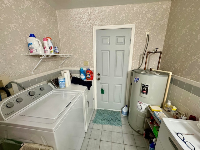 laundry room featuring light tile patterned flooring, washing machine and dryer, and water heater