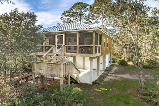 back of house with a wooden deck, a patio area, and a sunroom