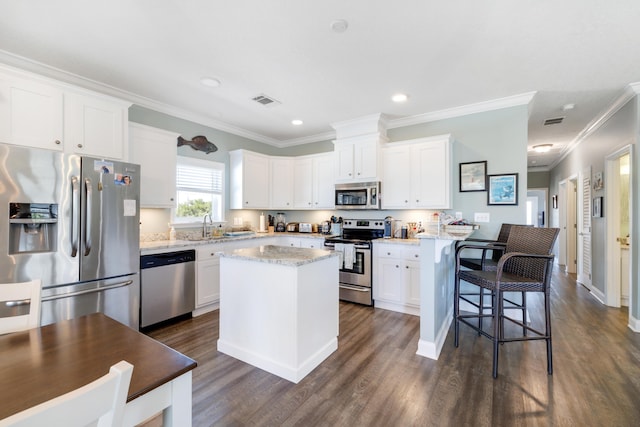 1548 Shell Point Rd, Crawfordville, FL 32327 - kitchen with stainless steel appliances, dark wood-type flooring, white cabinets, crown molding, and a breakfast bar area