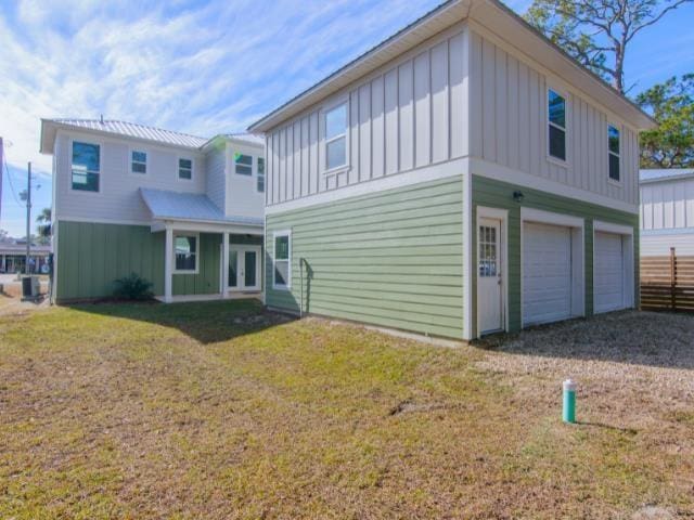 back of property featuring a garage, a yard, and cooling unit