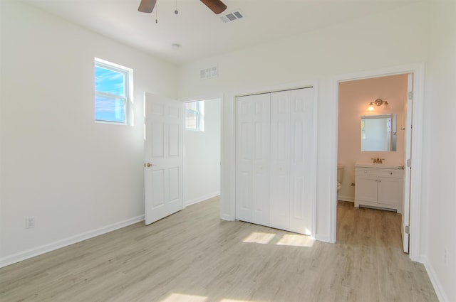 unfurnished bedroom with connected bathroom, sink, ceiling fan, light wood-type flooring, and a closet