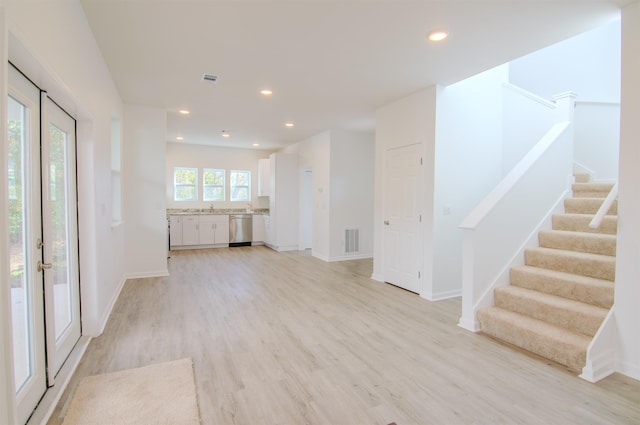 unfurnished living room with sink and light hardwood / wood-style floors