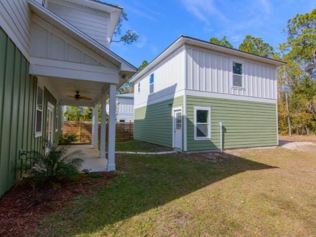 rear view of property featuring ceiling fan and a lawn