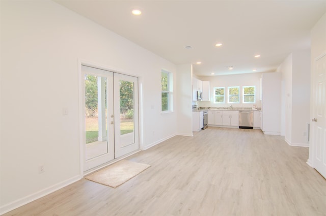 unfurnished living room featuring french doors, sink, and light wood-type flooring