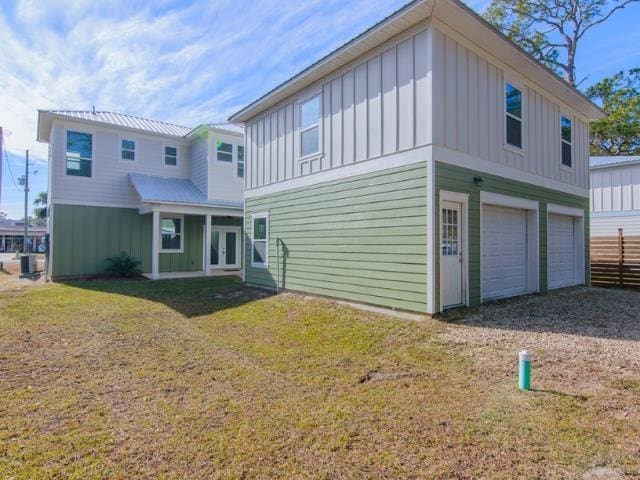 back of property featuring a garage and a lawn