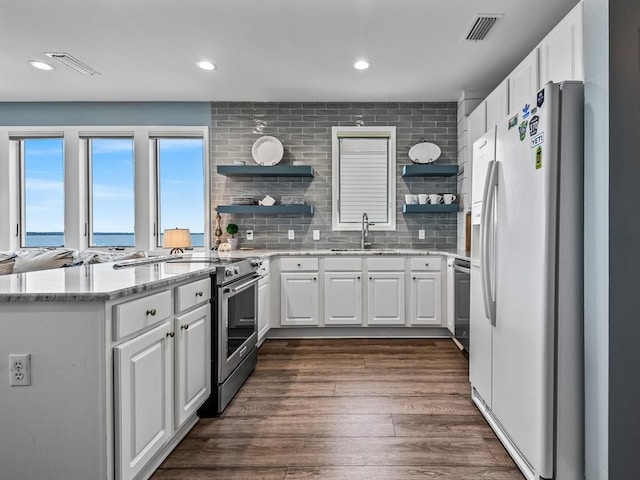 kitchen with a water view, stainless steel appliances, dark hardwood / wood-style flooring, white cabinetry, and sink