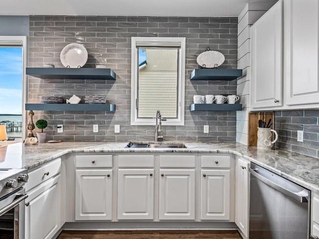 kitchen with light stone counters, tasteful backsplash, white cabinets, appliances with stainless steel finishes, and sink