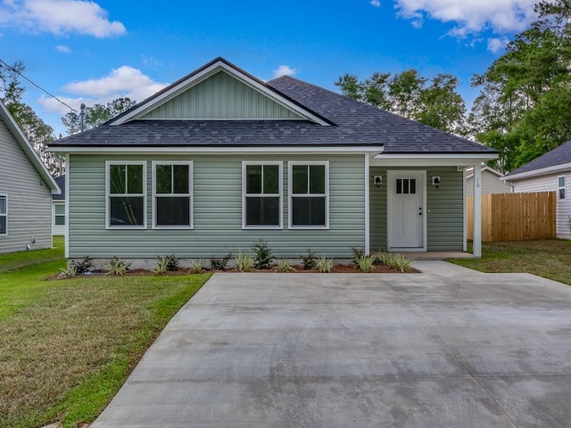 ranch-style house with a front lawn, roof with shingles, and fence