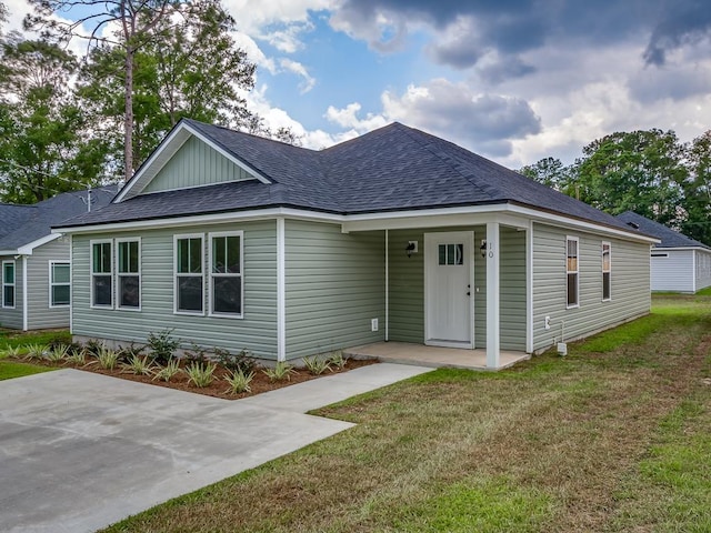 view of front facade with a shingled roof and a front lawn