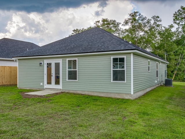 rear view of property with a yard, french doors, a shingled roof, and central air condition unit