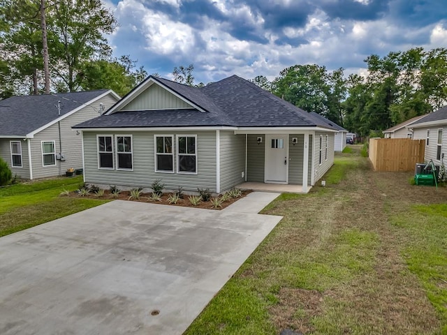 view of front of home featuring a shingled roof, fence, and a front lawn