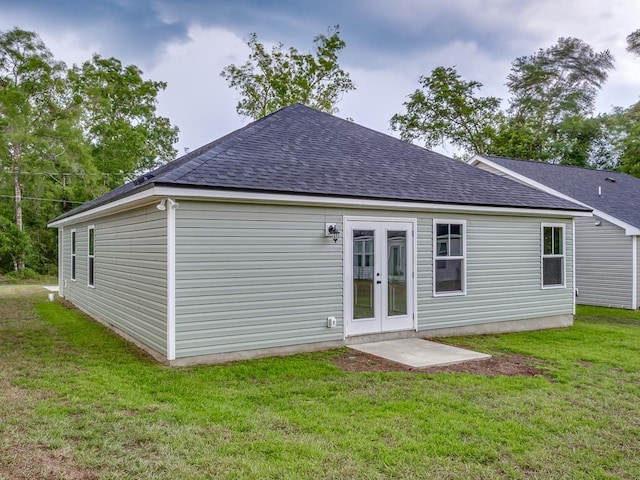 back of house with a shingled roof, french doors, and a lawn