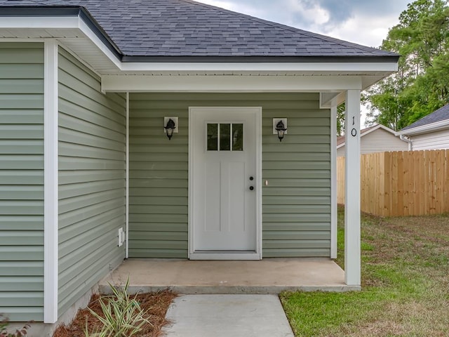 doorway to property with roof with shingles and fence