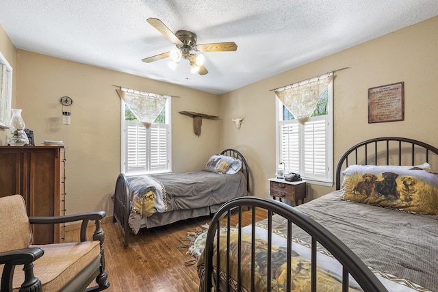 bedroom with multiple windows, dark hardwood / wood-style floors, and a textured ceiling