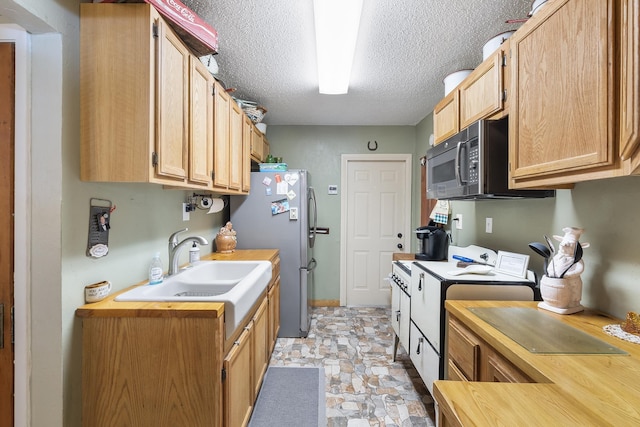 kitchen featuring sink, stainless steel fridge, range, a textured ceiling, and light brown cabinets