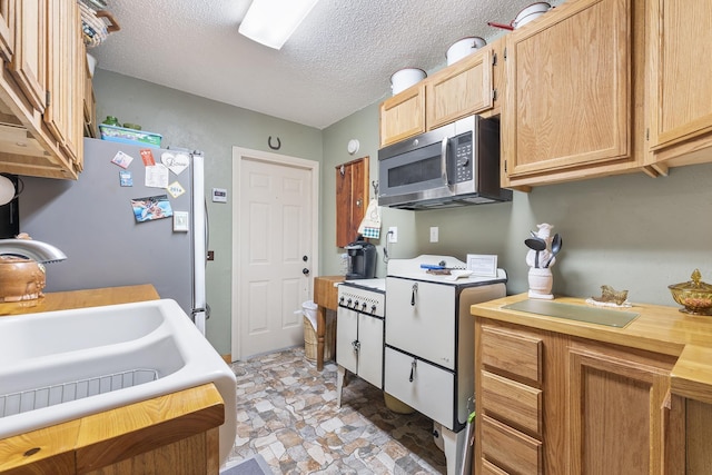 kitchen featuring stainless steel appliances, sink, a textured ceiling, and light brown cabinets