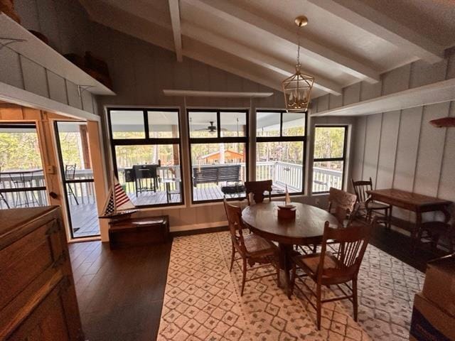 dining space featuring hardwood / wood-style flooring, a notable chandelier, a wealth of natural light, and vaulted ceiling with beams