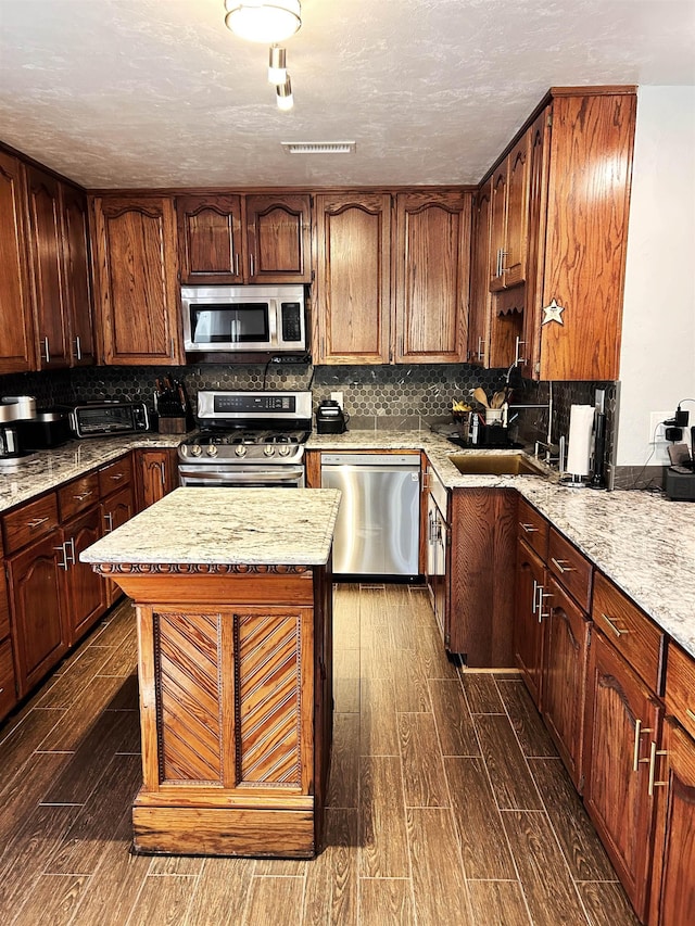 kitchen featuring tasteful backsplash, light stone countertops, a center island, and appliances with stainless steel finishes