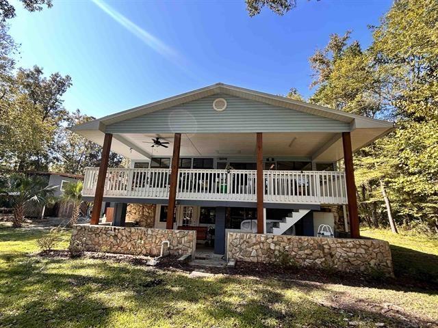 rear view of house with a wooden deck, ceiling fan, and a lawn