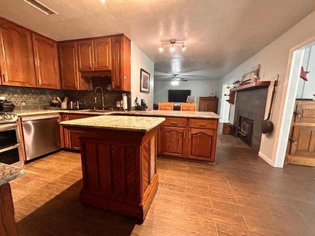 kitchen with sink, a center island, light wood-type flooring, dishwasher, and decorative backsplash