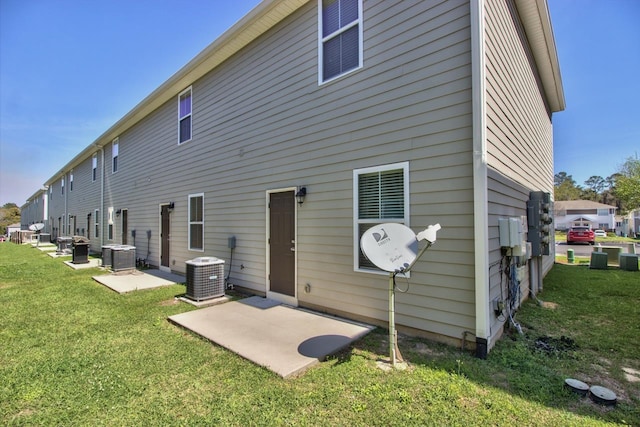 back of property with a lawn, central air condition unit, and a patio area