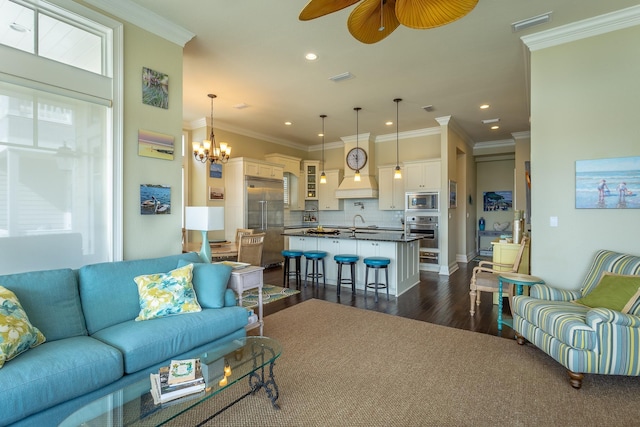 living room with dark hardwood / wood-style flooring, sink, ceiling fan with notable chandelier, and ornamental molding