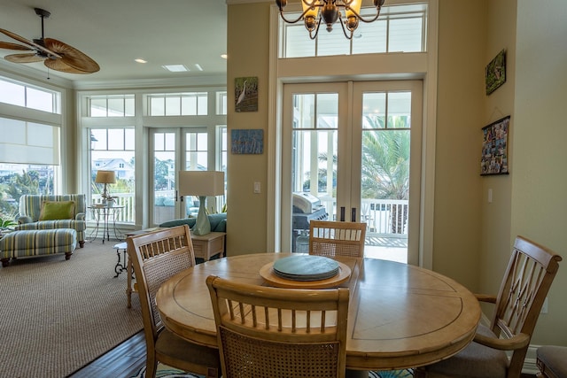 dining area with carpet flooring, ceiling fan with notable chandelier, and french doors