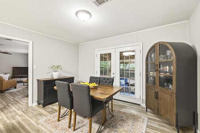 1816 Aaron Rd, Tallahassee, FL 32303 - dining area featuring french doors, light wood finished floors, crown molding, a decorative wall, and a textured ceiling
