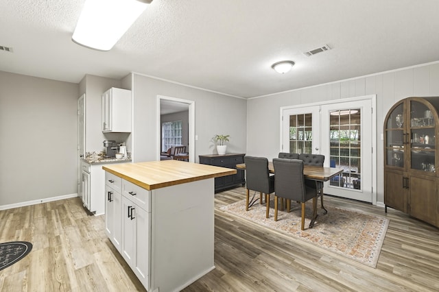 1816 Aaron Rd, Tallahassee, FL 32303 - kitchen featuring butcher block countertops, white cabinetry, light wood-style flooring, a textured ceiling, and crown molding