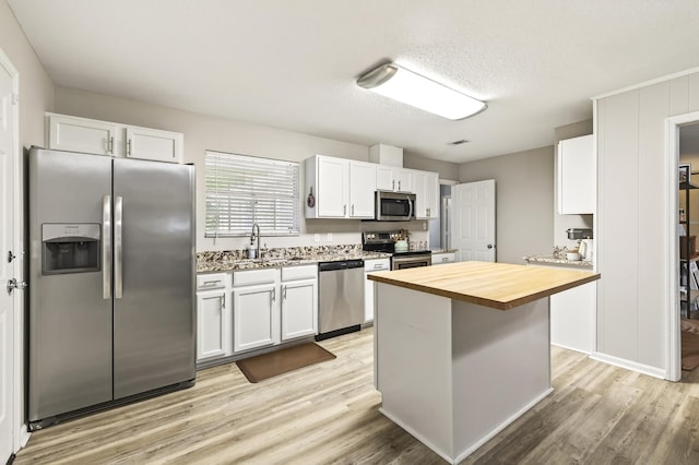 1816 Aaron Rd, Tallahassee, FL 32303 - kitchen featuring appliances with stainless steel finishes, butcher block countertops, white cabinets, light wood finished floors, and a textured ceiling