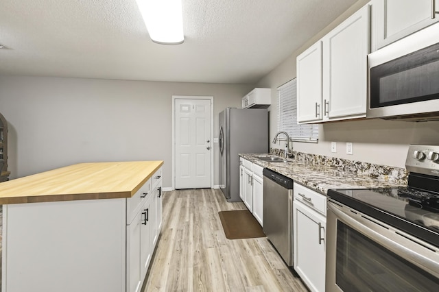 1816 Aaron Rd, Tallahassee, FL 32303 - kitchen with stainless steel appliances, butcher block countertops, light wood-style floors, white cabinets, and a center island