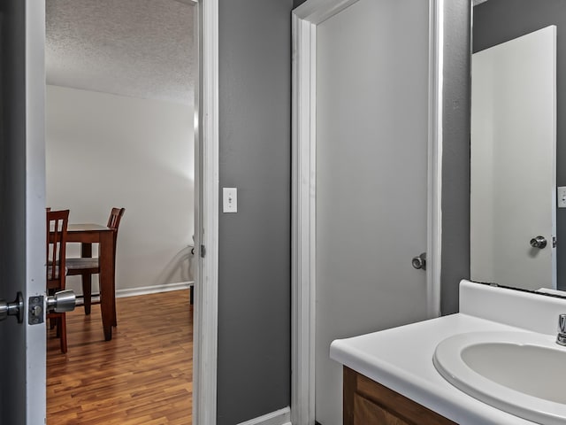 bathroom featuring baseboards, wood finished floors, a textured ceiling, and vanity