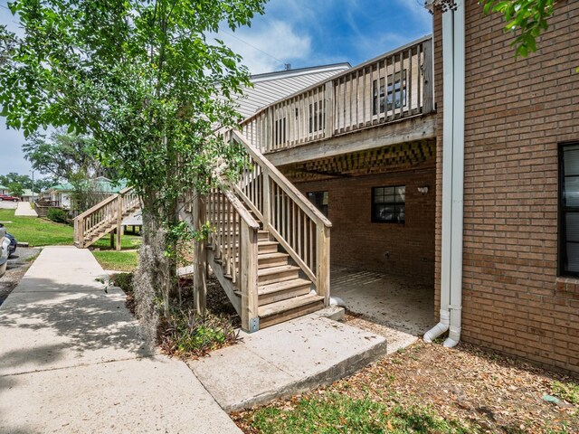 view of side of property with a wooden deck, stairs, and brick siding