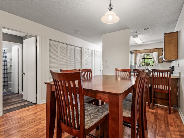 dining space featuring a textured ceiling, visible vents, and light wood-style flooring