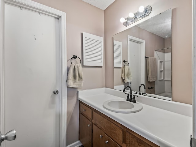 bathroom featuring a textured ceiling, a shower, and vanity