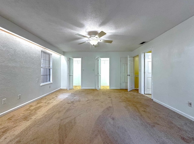 carpeted empty room featuring ceiling fan and a textured ceiling