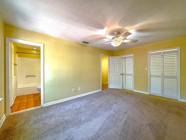 unfurnished bedroom with carpet flooring, ceiling fan, a textured ceiling, and connected bathroom