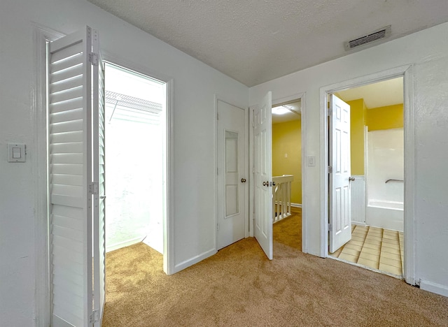 hallway featuring a textured ceiling and light colored carpet