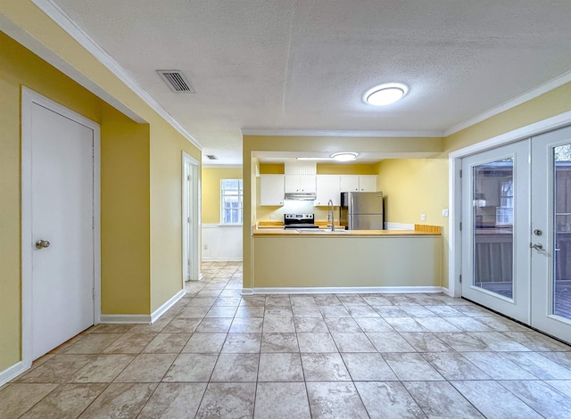 kitchen featuring stainless steel refrigerator, french doors, a textured ceiling, white cabinets, and ornamental molding