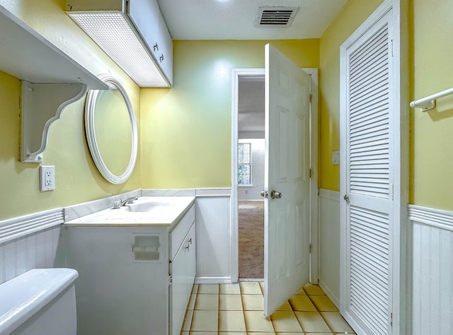 bathroom with tile patterned floors, vanity, toilet, and a textured ceiling