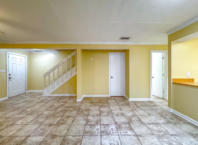 unfurnished room with a textured ceiling and ornamental molding