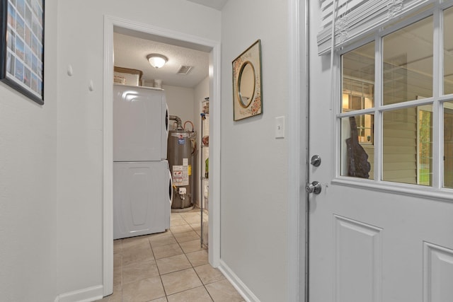 interior space with light tile patterned floors, visible vents, a textured ceiling, gas water heater, and washer / dryer