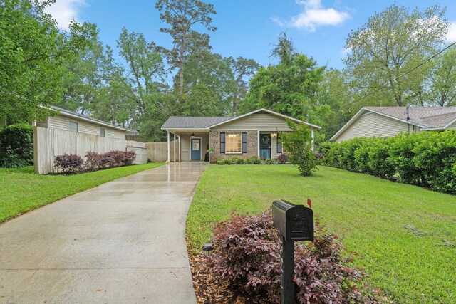 view of front facade featuring concrete driveway, fence, and a front lawn